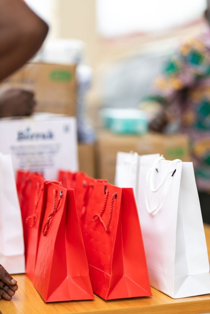 Red and white gift bags arranged on a wooden table, ideal for events or gifting purposes.
